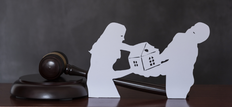paper cut of couple fighting over a house with gavel in the background