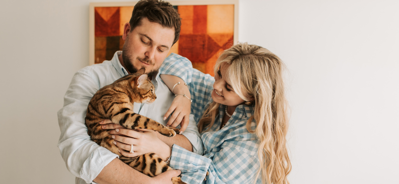 man holding a cat like a baby, woman petting the cat