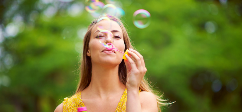 woman in yellow dress blowing bubbles