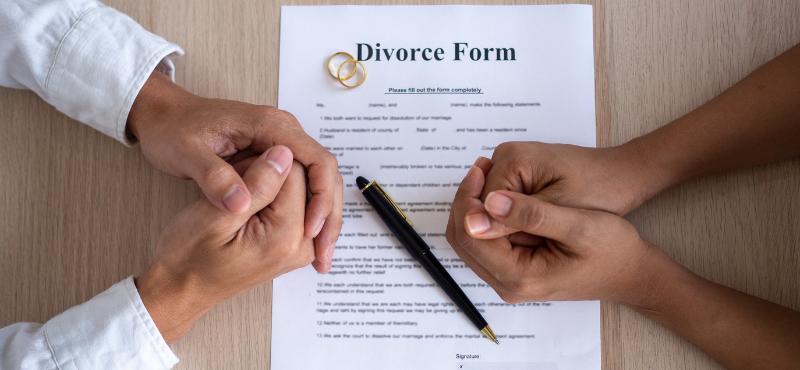 husband and wife clasped hands on a divorce form