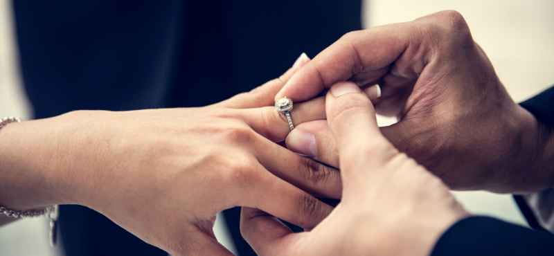closeup of man putting ring on woman's finger