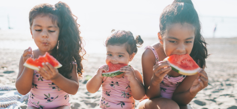 Children enjoying watermelon at the beach